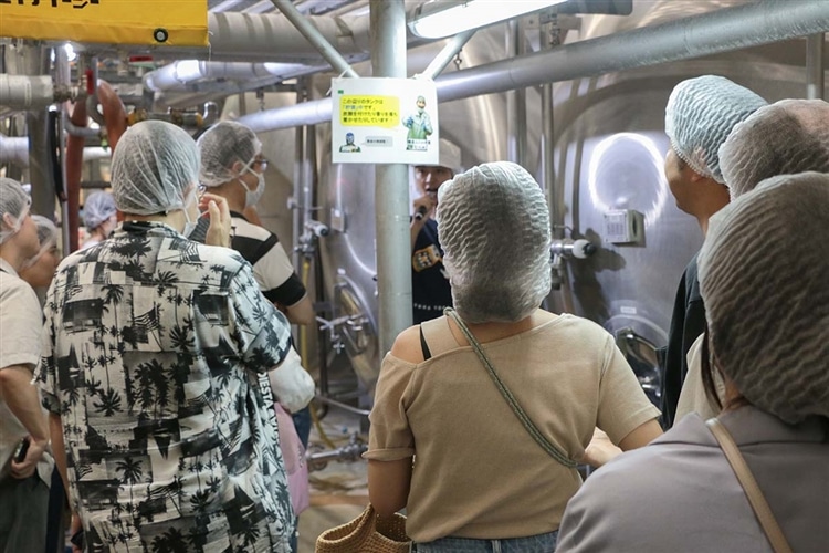ヤッホーブルーイングのスタッフが貯酒タンクの前でクラフトビールの熟成過程を説明している画像