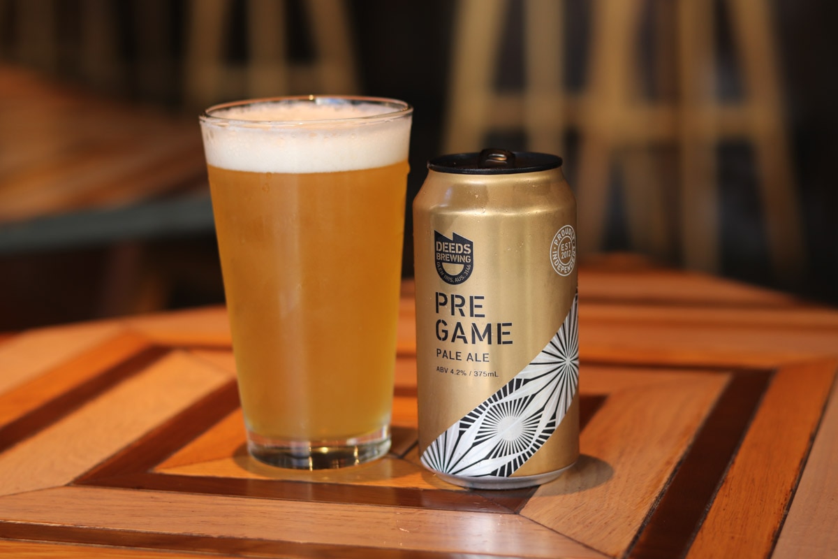 オーストラリアのブルワリーDEEDS BREWINGのクラフトビール「PRE GAME」がグラスに注がれて缶と一緒にテーブルの上に並んでいる画像
