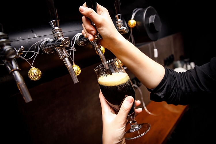 黒ビールをビールサーバーからグラスに注いでいる画像