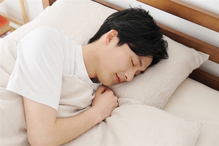 ベッドで眠る男性の画像