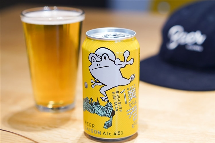 ヤッホーブルーイングが販売する、僕ビール君ビールの缶がテーブルの上に置かれている画像。左にはグラスに注がれたビールがあり、右にはネイビーのキャップがある