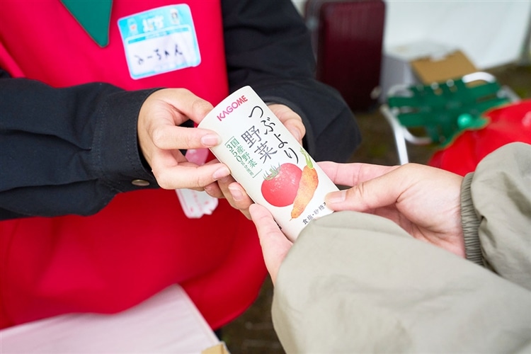 野菜ジュース「つぶより野菜」を参加者に配っている画像