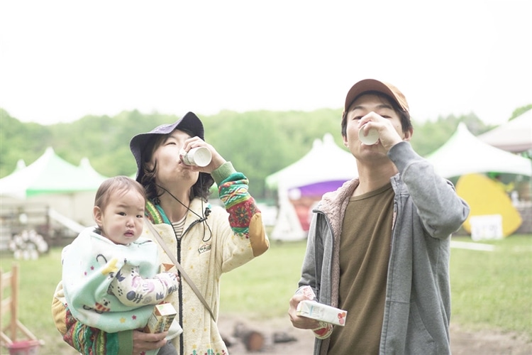 朝のキャンプ場で「つぶより野菜」を飲んでいる参加者たちの画像