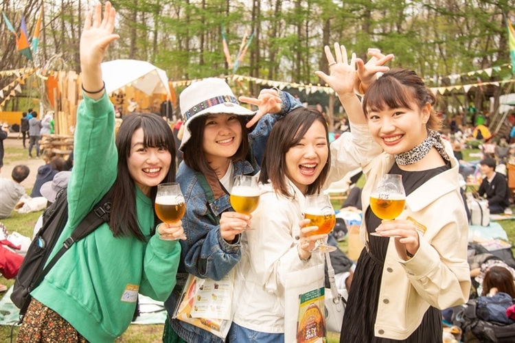 超宴の会場でビールを持った女性4名が笑顔で立っている様子