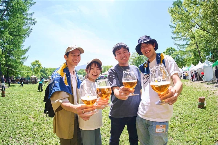 ビールを手にもつ、「よなよなエールの超宴2024 in 新緑の北軽井沢」の参加者（男性3名、女性1名）の写真