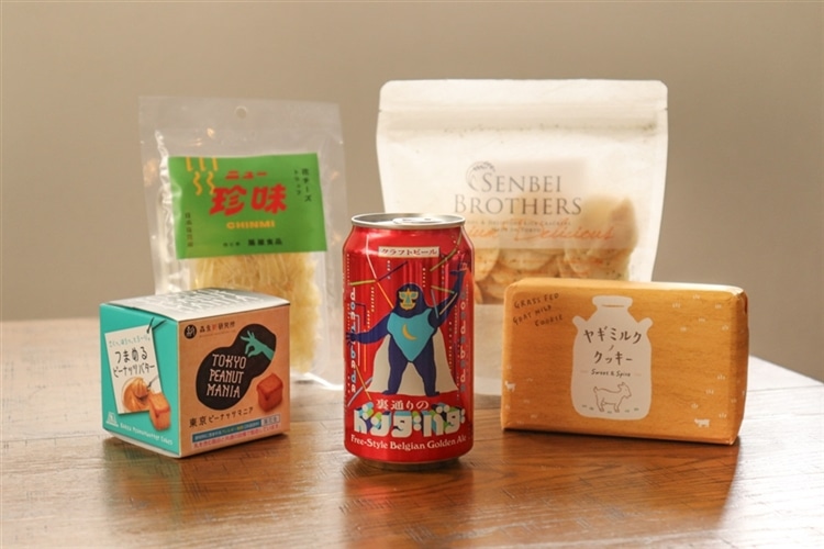 裏通りのドンダバダの缶と、日本百貨店のおつまみ4種が机の上に並んでいる様子