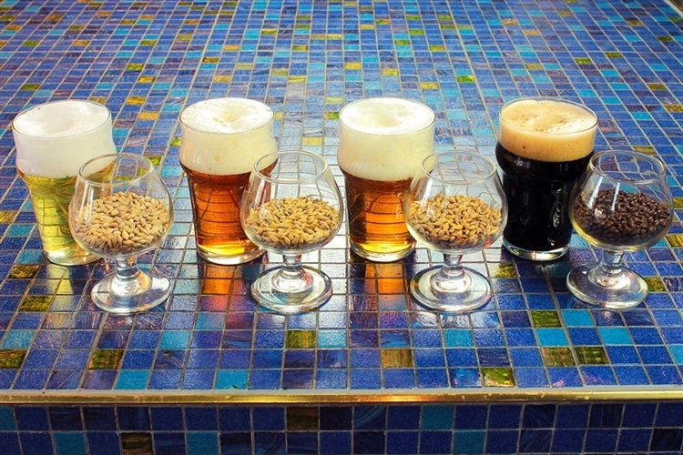 4種のビールが入ったグラス・麦が入ったグラスが1セットずつ・計4セット8脚並んでいる。左から右の順に、ビールの液色とその原材料である麦芽の色が、濃くなっていく。