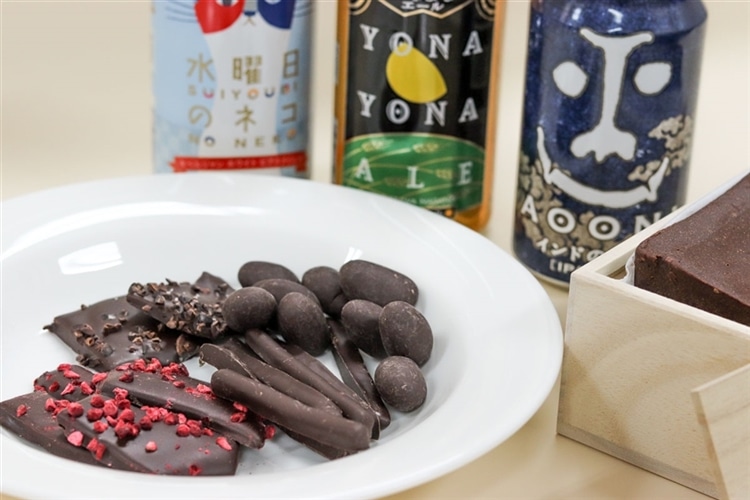 ダンデライオン・チョコレートの多種類のチョコレートがお皿の上に並び、後ろにヤッホーブルーイングのクラフトビールが見えている様子