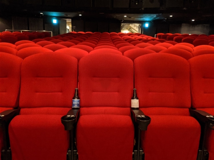 テアトル新宿の劇場内で、クラフトビールを椅子の上に乗せて映画を観せている様子