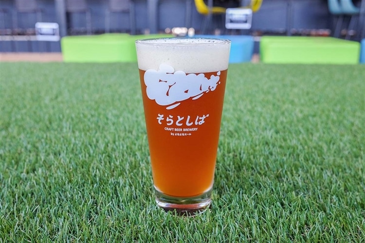 そらとしばシーズナルビールの第三弾が、グラスに注がれ芝の上に置かれている画像
