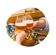 テーブルの上に食事が並び、クラフトビールで乾杯している画像