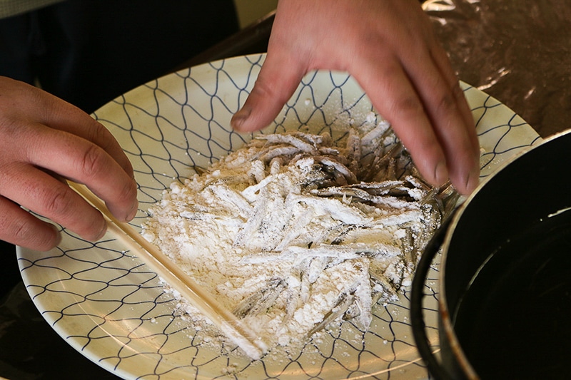 氷上で釣り上げたワカサギに小麦粉をまぶします